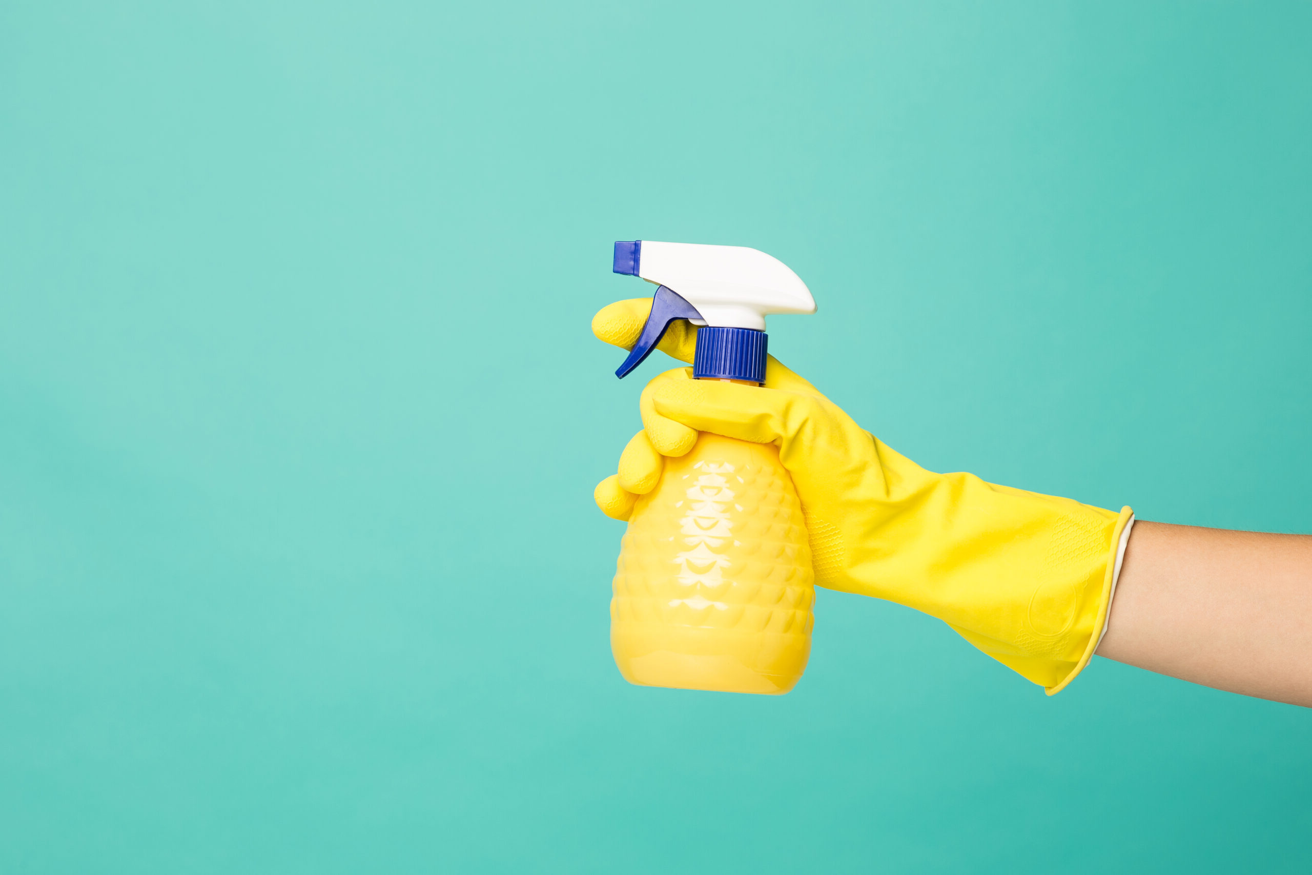 Close up picture of afemale hand and house-cleaning spray on a blue abstract background